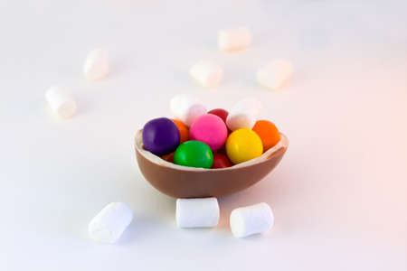 Purple, green, pink, yellow, orange, red candies, brown chocolate, white marshmallows on a white background. Selective focusの写真素材