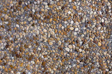 Orange, yellow, light stones and pebbles on a gray wall, background, textureの写真素材