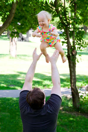 Father throwing daughter in the park. Smiling, laughing, summerの写真素材