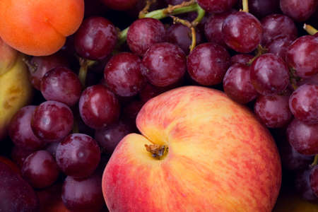 Closeup still life of ripe purple violet grapes, yellow apricot and red peach, summer, harvestの写真素材
