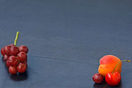Grapes, apricot, cherry on black blue wooden background with copy space, summer, autumn harvestの写真素材