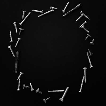 Set of shiny metal silver screws bolts on black wooden background with copy space, labor day cardの写真素材