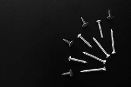Set of shiny metal silver screws bolts on black wooden background with copy space, labor day cardの写真素材