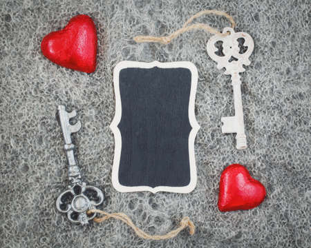 Closeup macro texture of knitted wool grey shawl with two red hearts, victorian keys and wooden...