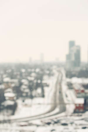 Blurred scenic view landscape of winter city suburbs, houses, skyscrapers and road, toned filtersの写真素材