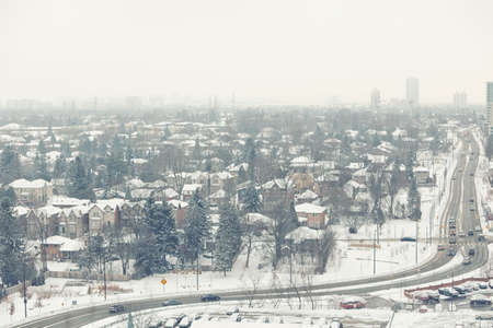 Scenic view landscape of winter city suburbs with cars on the road, houses and skyscrapers, toned  filtersの写真素材