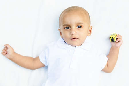 Portrait of cute adorable smiling laughing little indian mixed race south asian  infant boy in white...