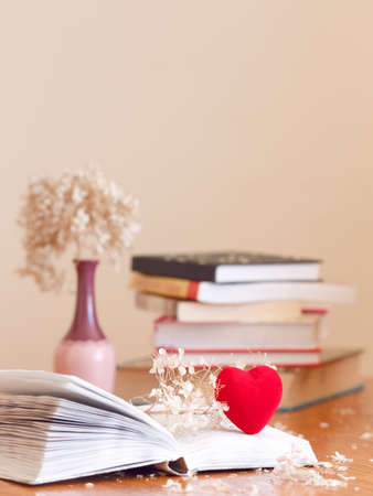 Closeup of open book with withered flowers hydrangea and a small red heart, pile of books on the background on wooden table, soft focus blurry, copyspace for text, concept of autumn, fall, education, nostalgic lookの写真素材