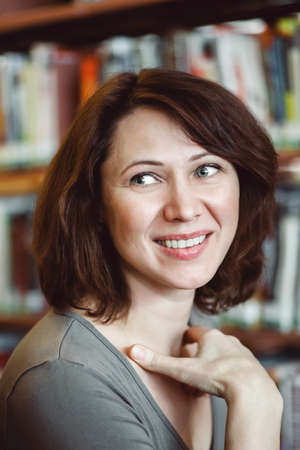 Closeup portrait of smiling middle age mature woman student in library looking away, teacher librarian profession, back to school conceptの写真素材