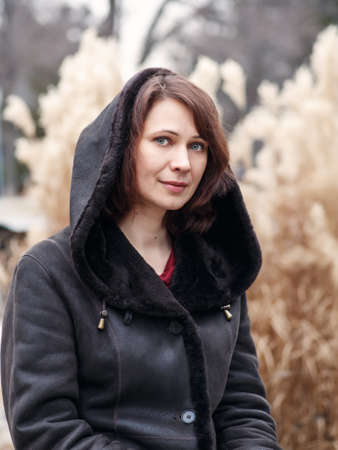 Closeup portrait of beautiful middle age white caucasian brunette woman with green eyes in coat jacket on fall autumn day outside looking in camera on yellow rye backgroundの写真素材
