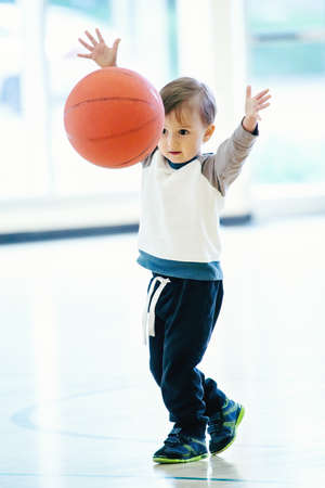 Cute adorable little small white Caucasian child toddler boy playing with ball in gym, having fun, healthy lifestyle childhood conceptの写真素材