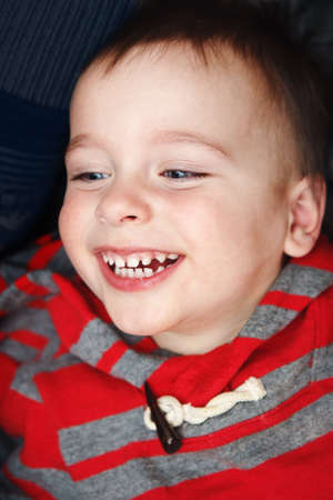 Close-up portrait of cute funny hilarious white Caucasian little boy toddler lying on bed and...