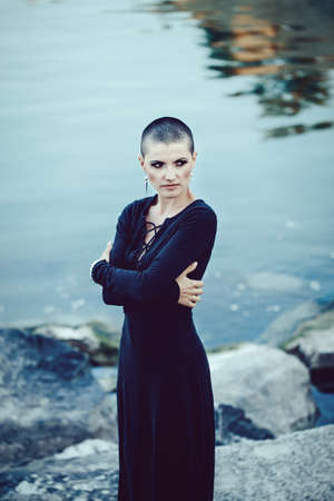 Portrait of sad beautiful Caucasian white young bald girl woman with shaved hair head standing by...