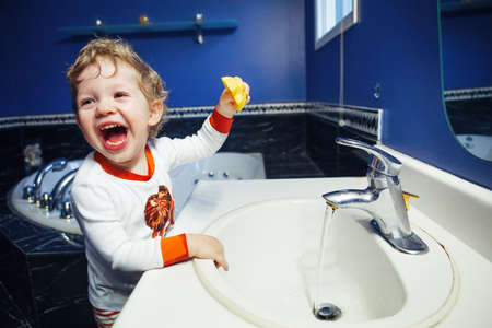 Closeup portrait of child kid toddler boy girl in bathroom toilet washing face hands playing with water, lifestyle home style, everyday moments, morning bedtime routineの写真素材