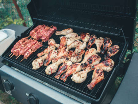 Closeup macro of raw meat barbecue chicken legs thighs on grill fireの写真素材