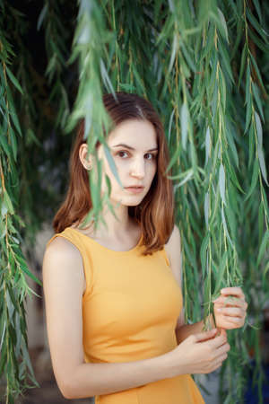 Closeup portrait of pensive sad beautiful young Caucasian woman girl in yellow dress with red hair, brown eyes, looking in cameraの写真素材
