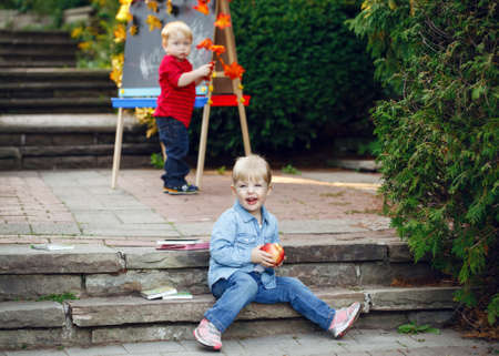 Group of two white Caucasian toddler children kids boy and girl outside in summer autumn park by...