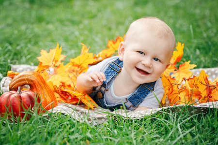 Portrait of cute funny adorable blond Caucasian baby boy with blue eyes in t-shirt and jeans romper...