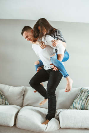Portrait of young beautiful funny couple man woman in love having fun standing on bed piggyback...