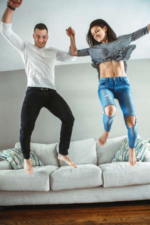 Portrait of young beautiful funny couple man woman in love having fun jumping from bed indoors at home, authentic lifestyle with real people, toned with filters, motion blur effectの写真素材
