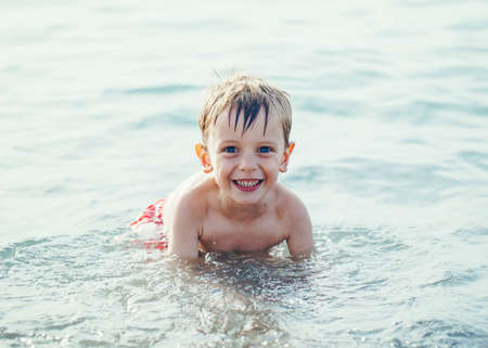 Portrait of funny adorable smiling laughing white Caucasian one young little boy in water ocean sea, emotional active healthy lifestyle summer moodの写真素材