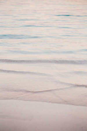 Closeup macro shot of sea ocean wave water with white foam, sandy beach background with copyspace....