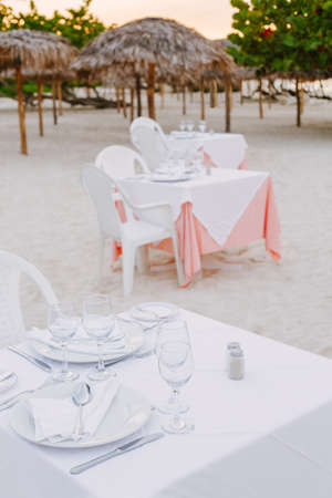 Group row of many tables standing on sea ocean sand beach at sunset, toned with filters in retro vintage film style, summer vacation landscapeの写真素材