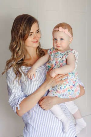 Closeup portrait of beautiful white Caucasian woman mother holding cute adorable blonde baby girl...