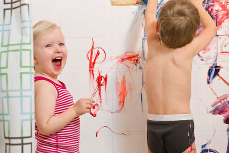 Portrait of two cute adorable white Caucasian little boy and girl playing painting on walls  in bathroom, having fun, lifestyle active childhood concept, early education developmentの写真素材