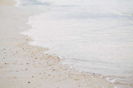 Closeup macro shot of sea ocean wave water with white foam, sandy beach background with copyspace. Toned with retro vintage film effect style filters, pastel faded colorsの写真素材