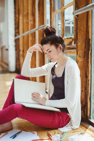 Portrait of beautiful white Caucasian young brunette woman student, female artist, sitting on floor...