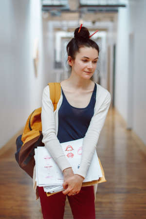 Portrait of beautiful white Caucasian young brunette woman student, female drawing designer artist, in hall of college university, person at work, hobby activity conceptの写真素材