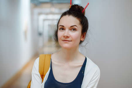 Portrait of smiling laughing white Caucasian brunette young beautiful woman student with pencils in...