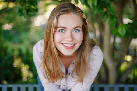 Closeup portrait of beautiful smiling white Caucasian girl woman with long blonde  hair and blue...