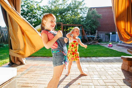 Portrait of  two little girls  sisters having fun on home backyard. Friends girls making silly...