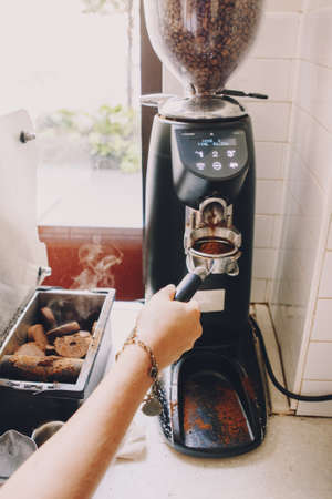 Closeup of Caucasian barista hand with filter holder grinding  fresh roasted coffee beans. Preparing coffee in coffee shop cafe.の写真素材