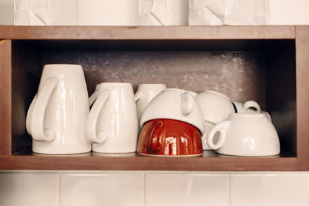 White coffee cups stacked on shelf in coffee shop. Interior of cafe with tea mugs. Toned with filters. Retro vintage style.の写真素材