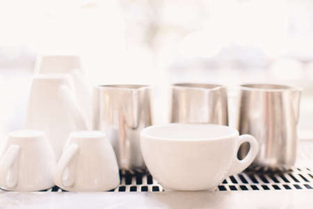 White coffee cups in coffee shop. Interior of cafe with tea mugs and milk jugs. Toned with filters with pastel colors. Retro vintage style.の写真素材