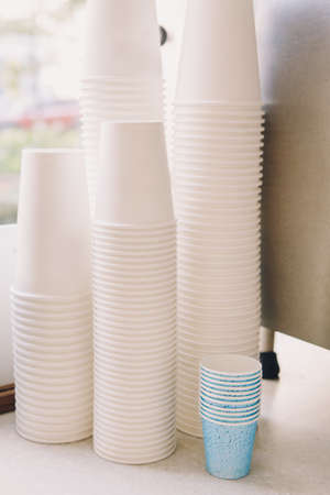 White coffee paper cups in coffee shop. Interior of cafe with tea mugs. Toned with filters. Retro vintage style.の写真素材