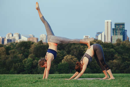 Two young beautiful Caucasian women yogi doing acro yoga pose. Women doing stretching workout in...
