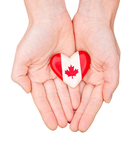 Macro closeup shot of hands palms holding round heart badge with red white canadian flag maple leaf, isolated on white background. Canada Day national celebrationのeditorial素材