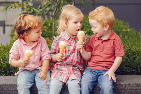 Group portrait of three white Caucasian cute adorable funny children toddlers sitting together...