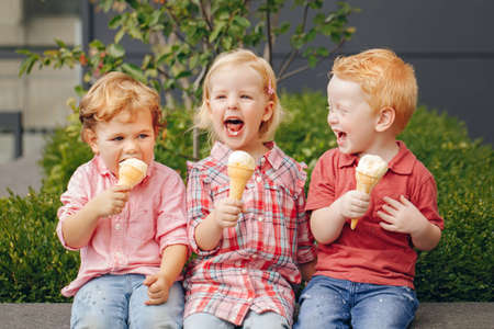 Group portrait of three white Caucasian cute adorable funny children toddlers sitting together sharing ice-cream food. Love friendship fun concept. Best friends forever.の写真素材