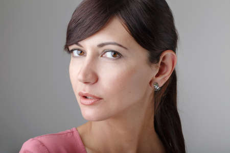 Closeup portrait of beautiful surprised young brunette Caucasian woman with brown eyes looking in...