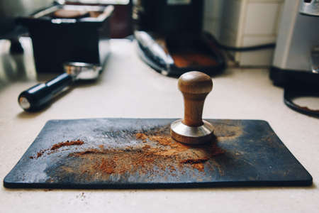 Closeup macro of tamper for pressing ground coffee into portafilter to make espresso hot drink. Small local business work in cafe.の写真素材