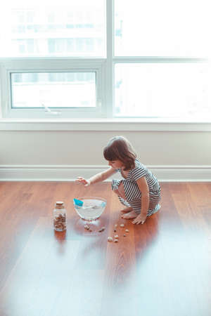 Portrait of cute white Caucasian preschooler girl playing with paper ships and water indoors at home. Early creativity  development, children activity. Dreams of adventure travel conceptの写真素材