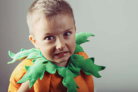 Portrait of adorable funny white Caucasian boy dressed as pumpkin for Halloween. Child playing...