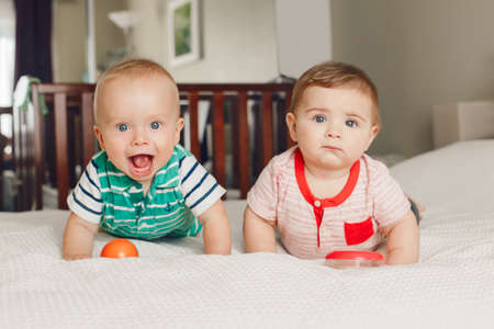 Group portrait of two white Caucasian cute adorable funny baby boys sitting together on bed sharing toy.Friendship childhood concept. Best friends forever. Early years developmentの写真素材