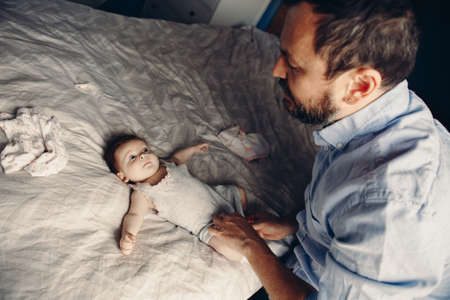 Middle age Caucasian father changing diaper for newborn baby daughter. Male man parent taking care of child at home alone. Authentic lifestyle candid moment. Single dad family life concept.の写真素材