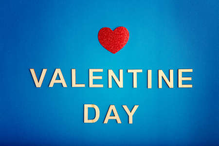 Happy Valentine Day. Beautiful card wallpaper with one red heart in centre on blue background. Gradient toned backdrop. Concept of love February holiday. Wooden words letters wishes.の写真素材
